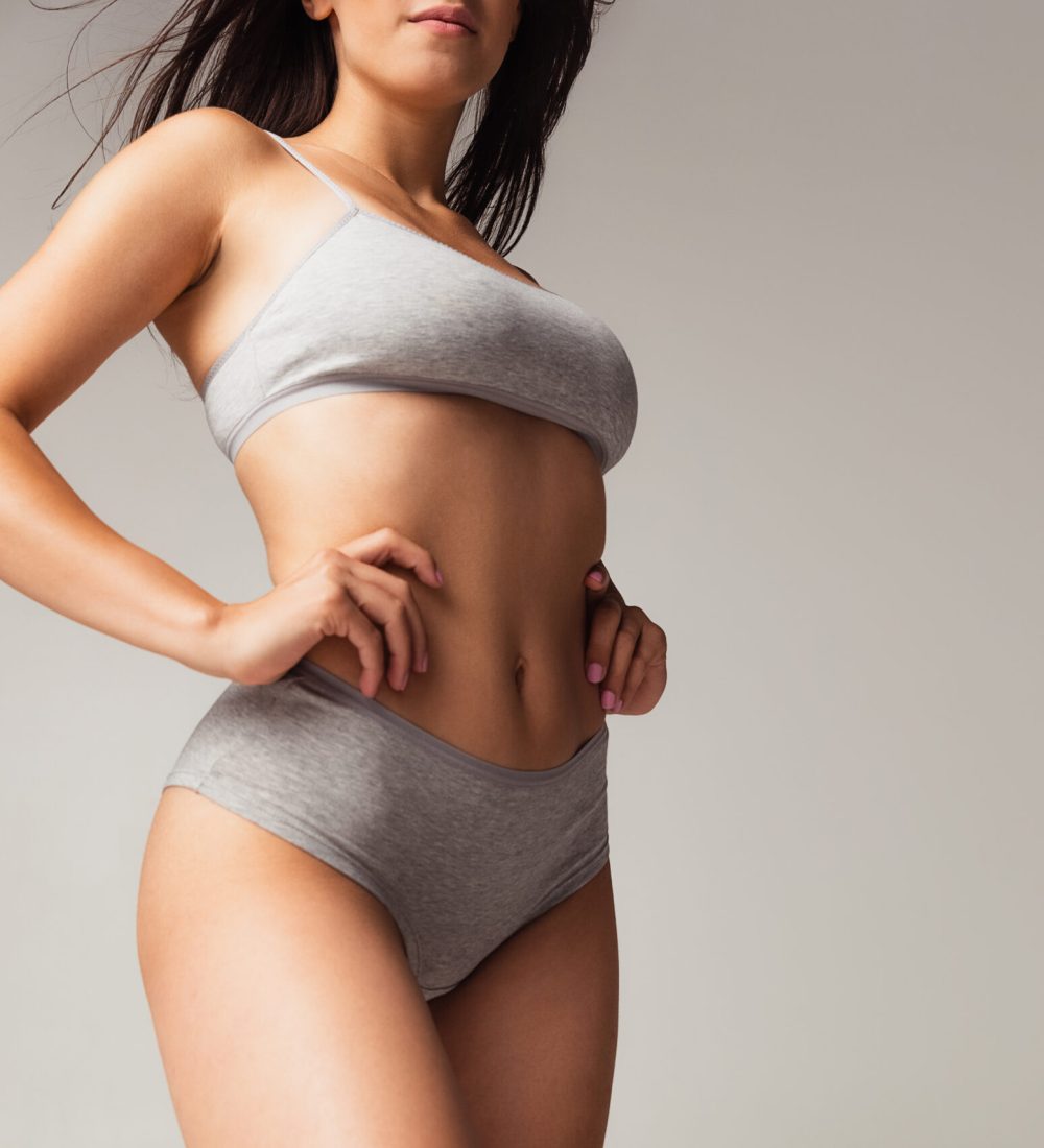 Perfect sportive shape. Adorable body of young caucasian woman isolated on gray studio background. Fit, healthy and strong authentical body. Natural beauty, treatment, healthcare, fitness and diet concept.